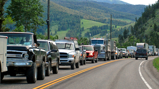 Line of vehicles backed up on one side to a rural road in Montana