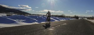 Silhouette of cyclist with snow drifts on roadside