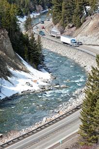 Semi Trucks and other vehicles travel along HWY 191 alongside the Gallatin River on the way to Big Sky.