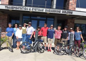 Twelve WTI and MDT staff members pose with bicycles in front of MSU transportation building.