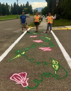 Volunteers pose with with painted street mural traffic calming project in Bozeman Montana 2019