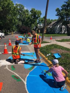 Volunteers paint traffic calming murals along residential street.
