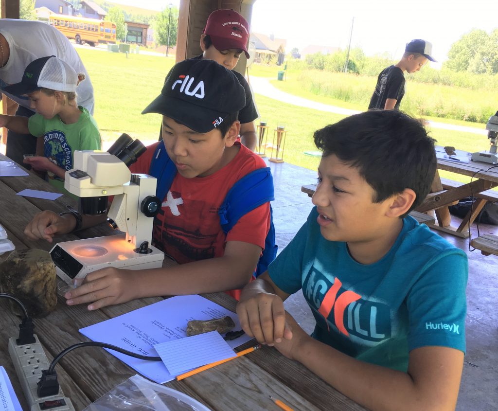 Students prepare to use a microscope during a camp activity 2019
